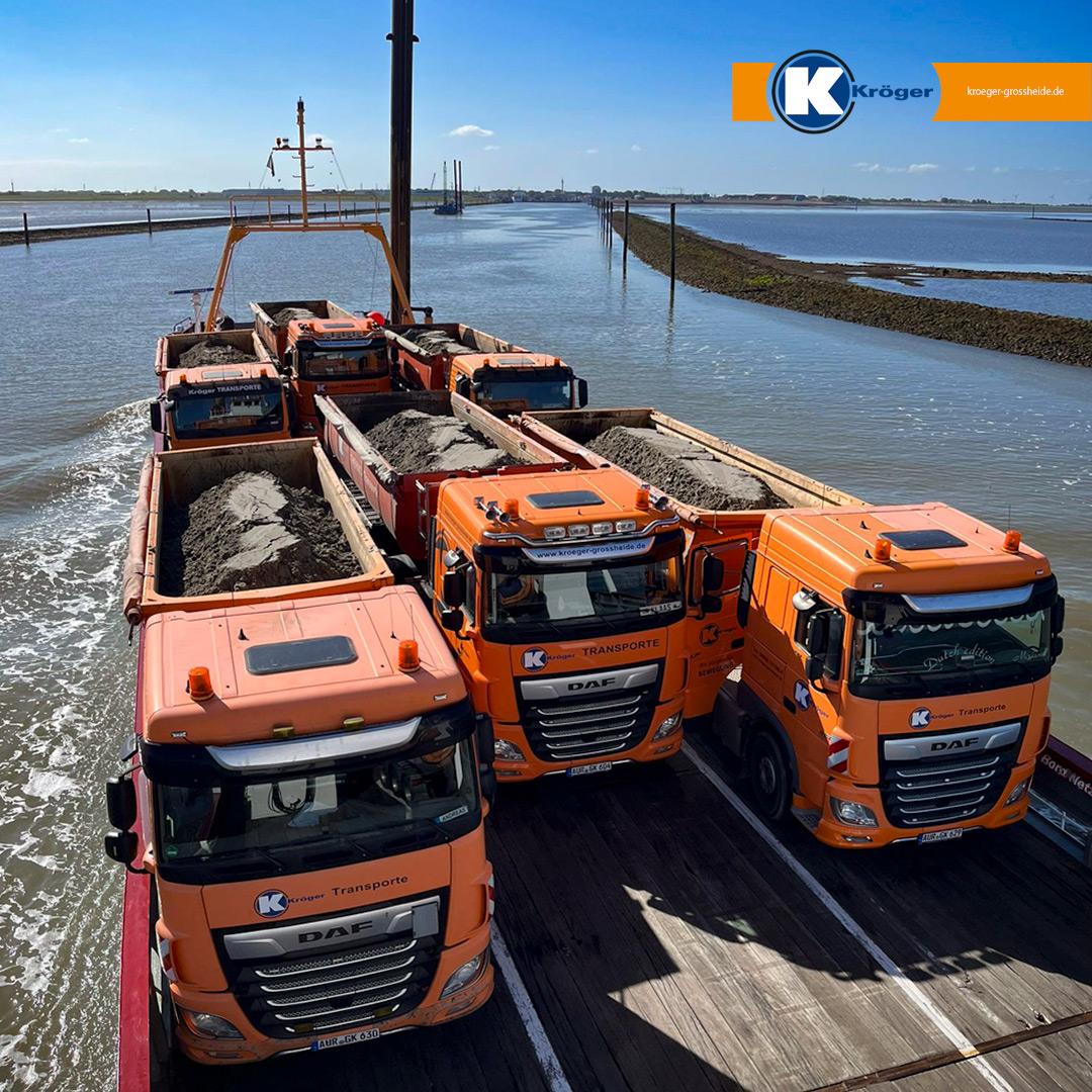 Orangefarbene LKW der Firma Kröger GmbH auf einer Fähre von Norderney nach Norddeich mit Bohrklein beladen.